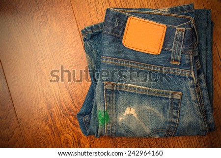old blue jeans with brown label on the belt smeared with green paint and a pocket full of holes, which were stored for a long time a mobile phone, instagram image style