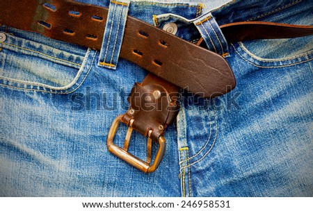 unfastened leather belt on old blue jeans