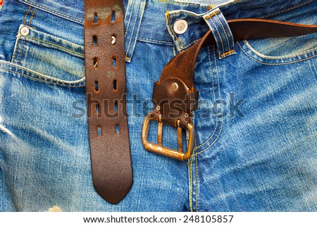 aged blue jeans with unfastened old leather belt