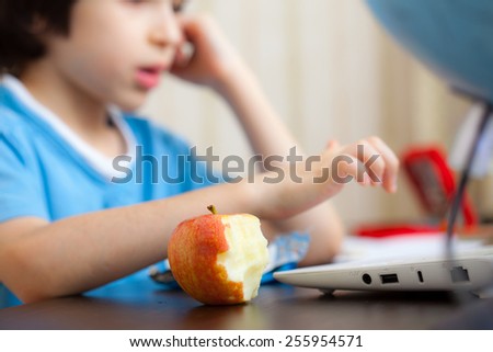 bitten apple and a boy with computer in class.  focus on a fruit
