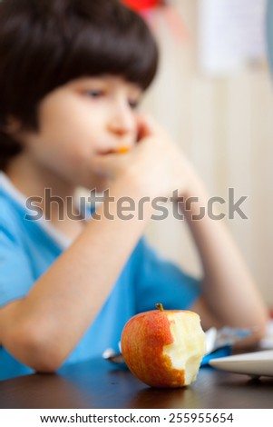 bitten apple and boy does his homework on the computer. focus on a fruit
