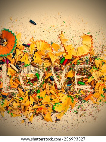 The word Love on the background of colored pencil shavings, vertical. instagram image retro style