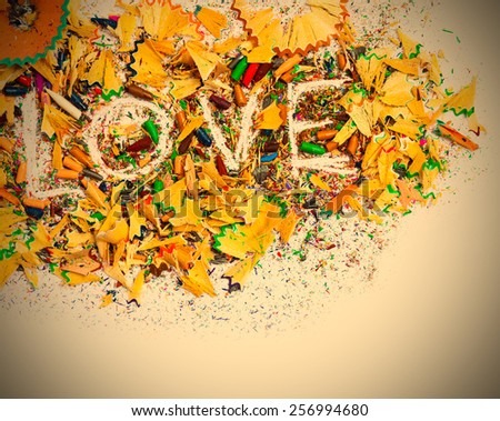 The word Love on the white background of colored pencil shavings with copy space. instagram image retro style