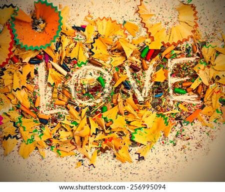 The word Love on the white background of colored pencil shavings. instagram image retro style