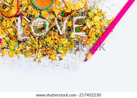 The word Love on the white background of colored pencil shavings with rose pen