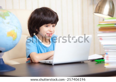smiling boy looking at a computer monitor, distance learning