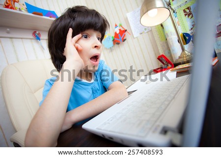 Surprised boy looking at a computer monitor, distance learning
