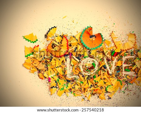 word Love over a shavings of colored pencils for drawing with copy space. instagram image retro style