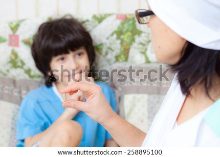 hand of a doctor with pill and smiling boy on the background