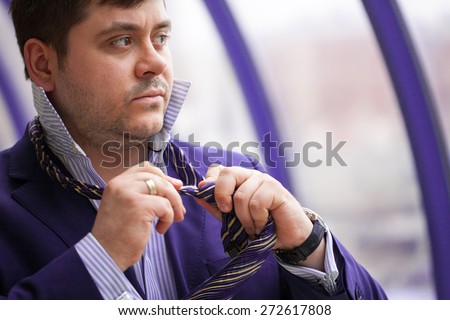 Serious businessman tying his tie before a business meeting