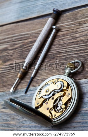 vintage pocket watch and a screwdriver. still life