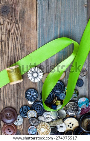 set of vintage buttons with green tape and spool of thread on aged boards of a old table