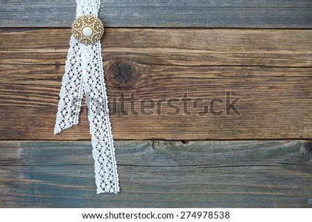 vintage lace with a brooch in the aged wooden surface