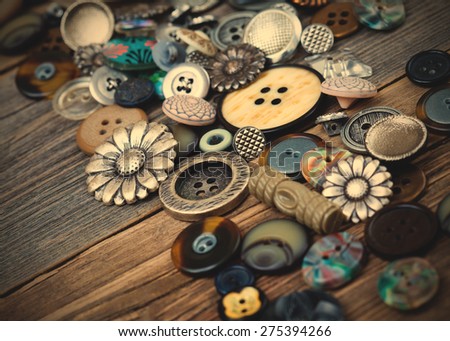 Vintage buttons in large numbers scattered on aged wooden boards of old desk. instagram image retro style