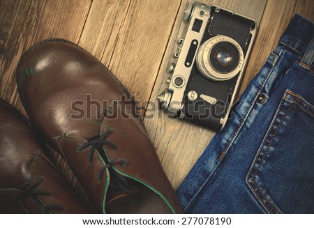 rangefinder camera, brown boots and blue jeans on the old wooden boards. Kit for the traveler. instagram image filter retro style