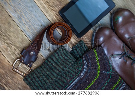 vintage belt, leather boots, sweater and digitizer on aged boards. still life