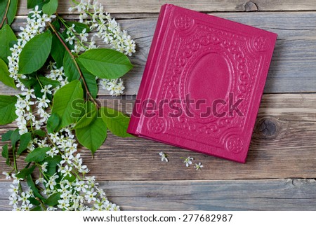 Blossoming bird-cherry and vintage book on the aged  boards of the ancient table. Still life
