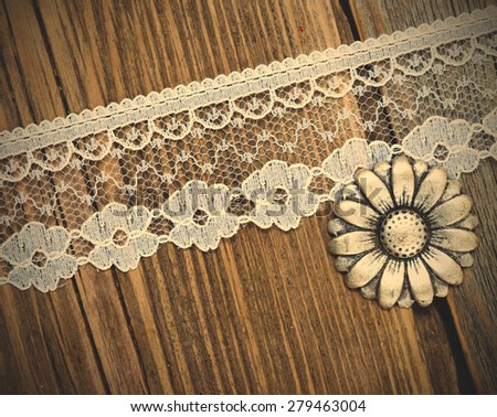 vintage button and lace tape on old wooden surface. instagram image filter retro style