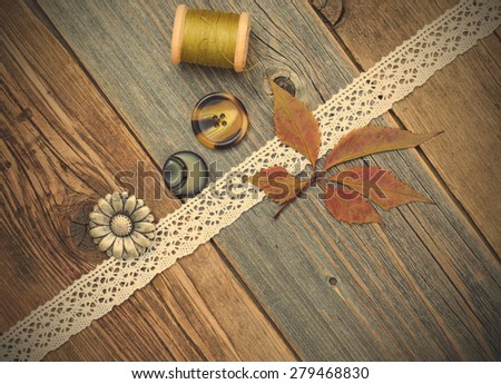 taylor still life with lace tape, vintage buttons, spools of thread and herbarium on the surface of an aged wooden boards. instagram image retro style