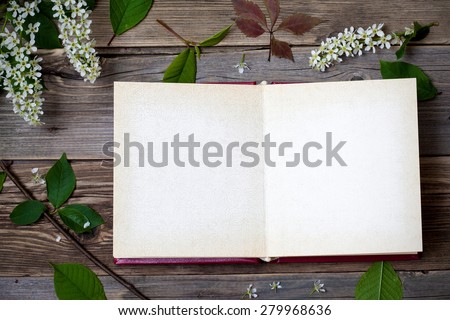 book with open pages and blossom bird-cherry  on aged boards of antique table