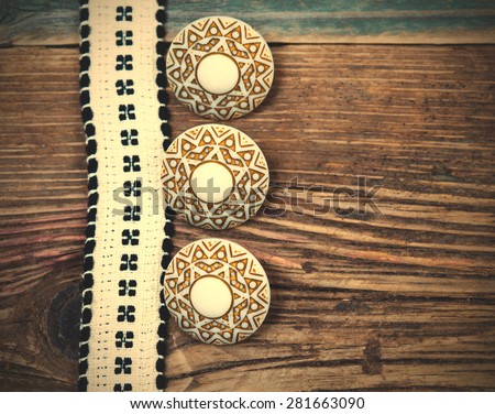 Vintage ribbon with embroidered pattern and three ancient buttons on the old textured boards. instagram image filter retro style