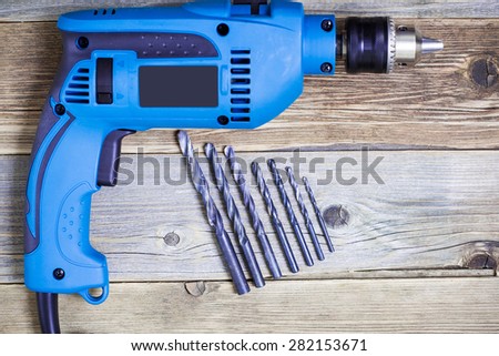 electric drill with a set of drill bits on the old workbench