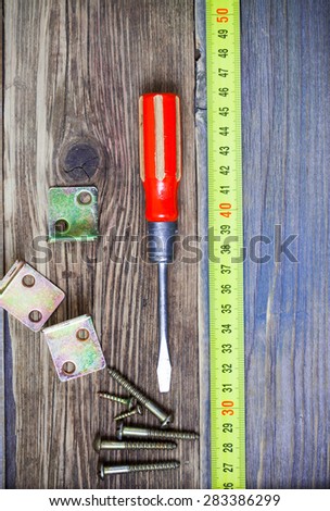Vintage screwdriver, screws, angles and measuring tape on old boardswith copy space