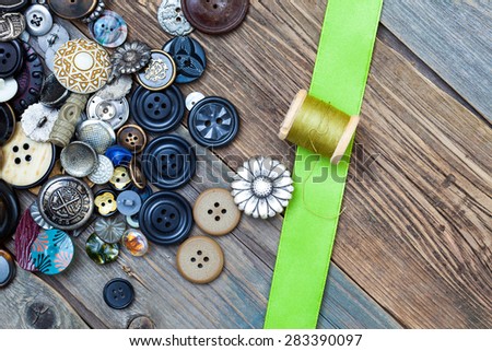 vintage buttons, spool with thread and green tape on aged textured boards