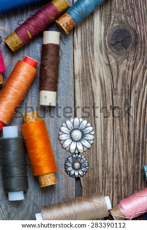 vintage buttons and oldÂ reels of varicolored thread on the textured surface of the ancient tailor\'s table with copy space