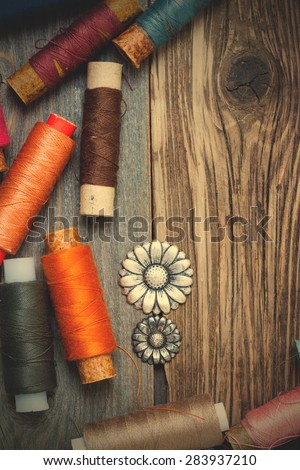 vintage buttons and oldÃ?ÃÂ reels of varicolored thread on the textured surface of the ancient tailor\'s table with copy space. instagram image filter retro style