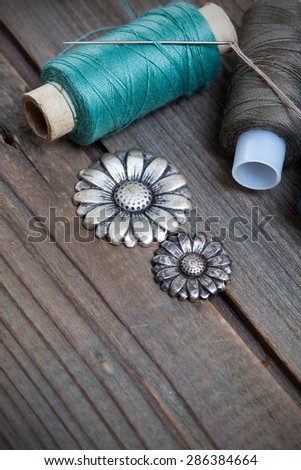 two spools of threads and vintage buttons flowers on the old boards