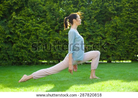 beautiful adult woman doing yoga on green grass in summer park