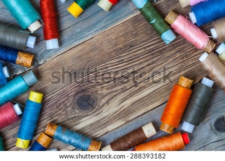 Vintage spools with multi colored threads on old tailoring table with copy space