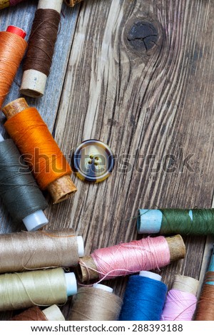 Vintage spools with multi colored threads and old button on old tailoring table