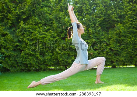 beautiful adult woman doing yoga on green grass in summer park