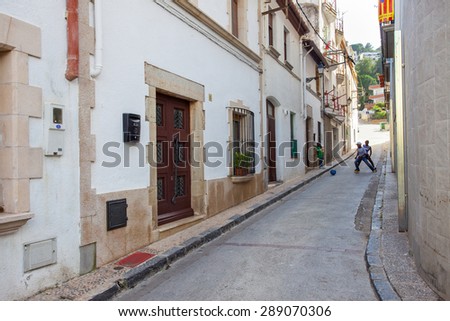 Tossa de Mar, Spain, June 17, 2013: Children play with a ball on the narrow streets of the medieval town