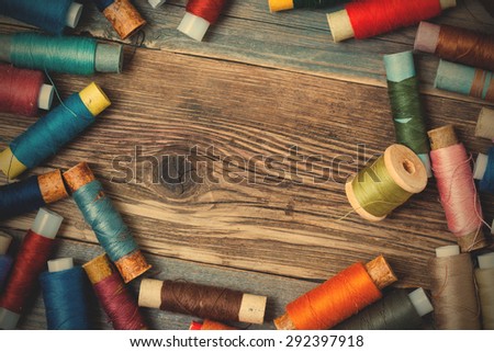Vintage spools with colored threads on old tailoring table with copy space. instagram image filter retro style