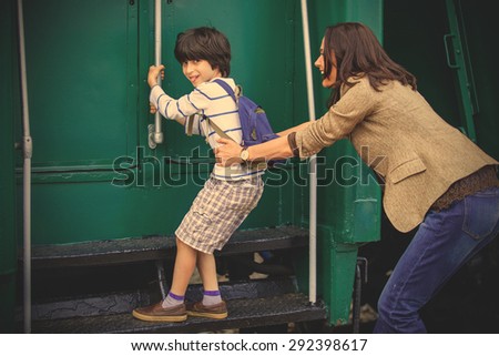 Boy traveler holds the handrail of the passenger railcar, as his mother holds his son\'s clothes. instagram image filter retro style