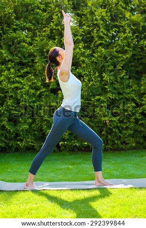 young woman doing yoga on green grass in park at summer day