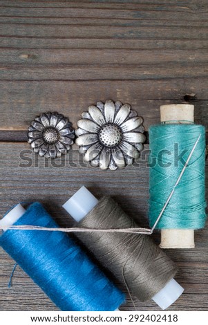 two vintage buttons flowers and spools with threads on old wooden surface