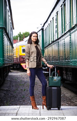 Businesswoman goes in retro voyage. At the train station near the passenger railcar in anticipation of a trip