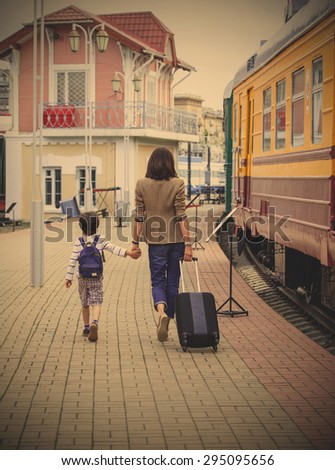 mother and son are on the platform of retro railway station along a vintage railcar. instagram image filter retro style
