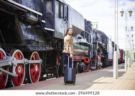 pretty adult woman goes in retro voyage. At the train station near the passenger railcar in anticipation of a trip
