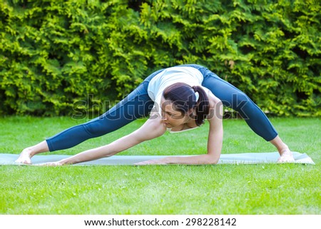 beautiful woman doing yoga in morning park on green grass