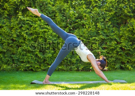 adult woman doing yoga in sunny morning park on green grass
