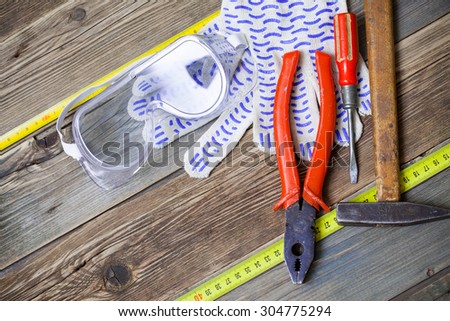 old pliers, ancient hammer, vintage screwdriver, safety gloves and glasses on aged boards