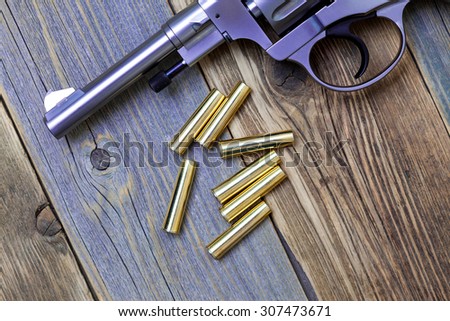 Nagan revolver with cartridges on aged wood background, close-up, part of