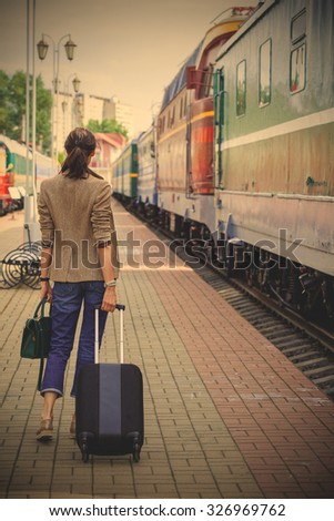 woman with luggage walking on the platform along the passenger train. returning from vacation. instagram image filter retro style