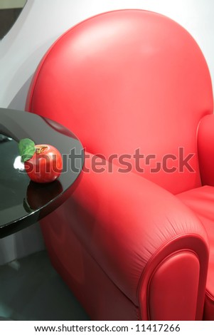 abstraction, fragment of the bright red leather easy chair with apple on edge of the table