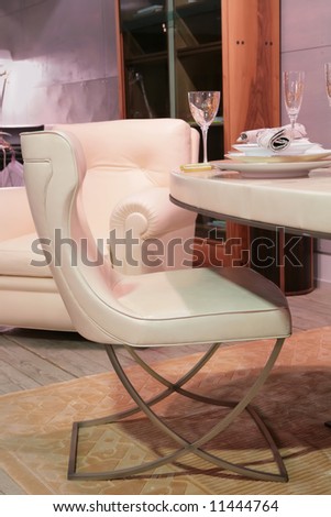beige leather easy chair in luxurious dinning-room beside table with goblet